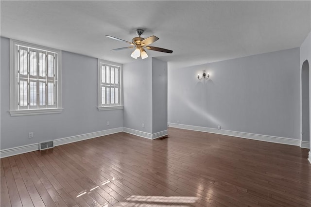 unfurnished room with a ceiling fan, visible vents, baseboards, arched walkways, and dark wood-style flooring