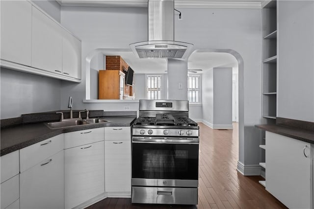 kitchen with open shelves, a sink, dark countertops, gas stove, and island range hood