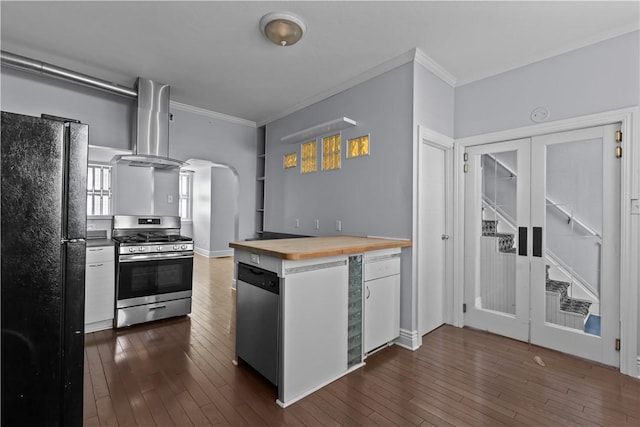 kitchen with arched walkways, appliances with stainless steel finishes, wall chimney exhaust hood, butcher block counters, and dark wood-style flooring