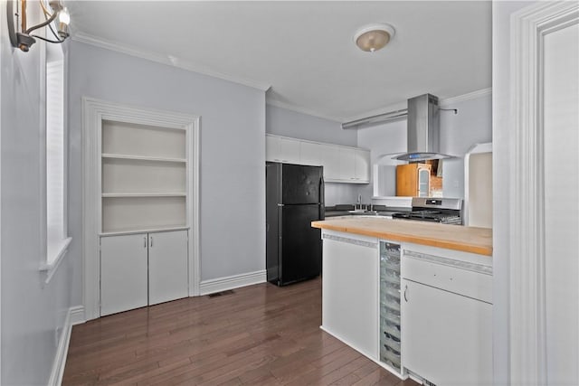 kitchen with dark wood-style floors, stainless steel range with gas cooktop, freestanding refrigerator, white cabinetry, and wall chimney range hood