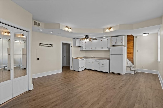 kitchen featuring white appliances, wood finished floors, visible vents, light countertops, and white cabinets