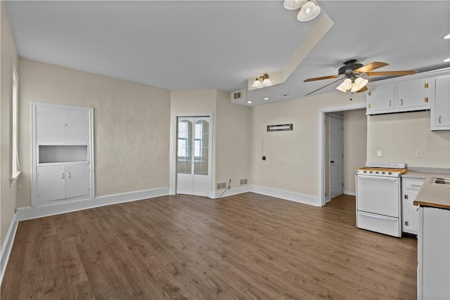 interior space with baseboards, wood finished floors, white cabinets, and electric stove