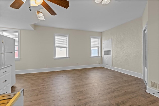 empty room with wood finished floors, baseboards, and ceiling fan