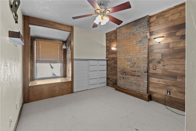 unfurnished bedroom with a ceiling fan, wood walls, and carpet flooring