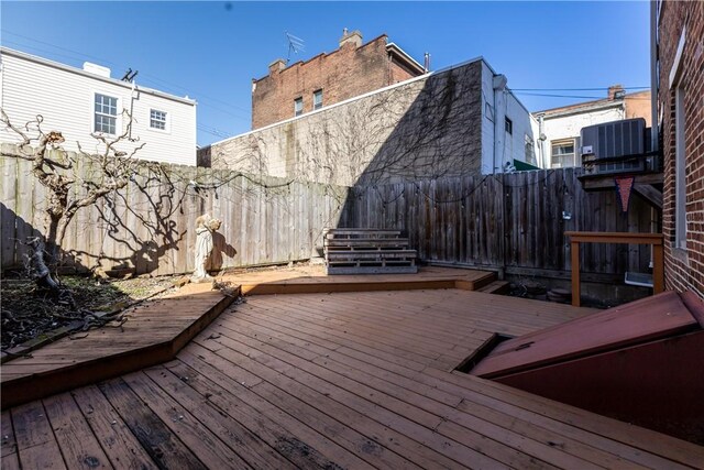 wooden terrace featuring central air condition unit and a fenced backyard