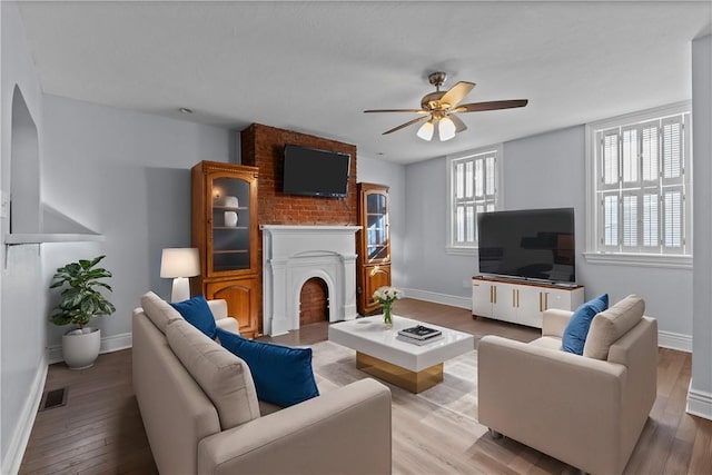 living room with visible vents, baseboards, wood finished floors, and a fireplace