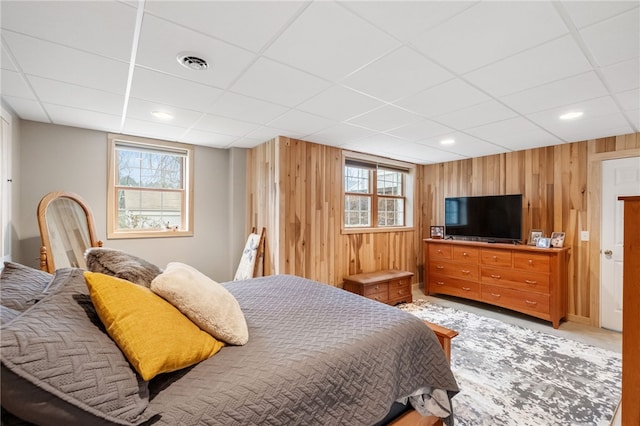 bedroom featuring visible vents, a paneled ceiling, and wood walls