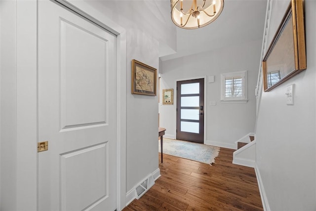 entrance foyer with visible vents, stairway, baseboards, a chandelier, and dark wood-style flooring