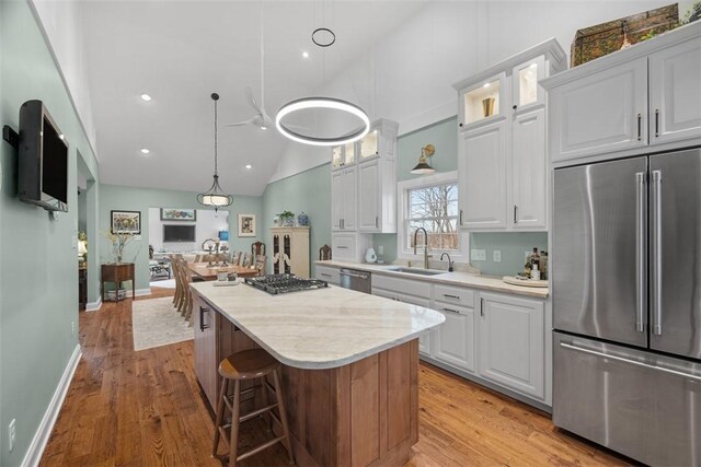 kitchen with light wood-style flooring, a center island, appliances with stainless steel finishes, and a sink