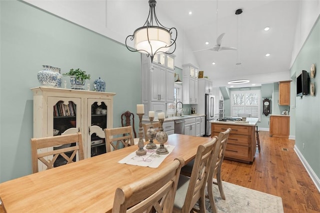 dining area with baseboards, light wood-type flooring, recessed lighting, high vaulted ceiling, and a ceiling fan