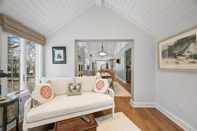 sitting room featuring baseboards, lofted ceiling, wood finished floors, and wooden ceiling