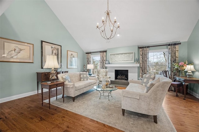 living area featuring baseboards, high vaulted ceiling, wood finished floors, and a fireplace