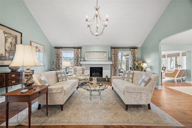 living area with wood finished floors, a brick fireplace, a healthy amount of sunlight, and baseboards