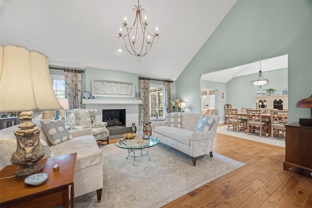 living area featuring a chandelier, a fireplace, high vaulted ceiling, and hardwood / wood-style flooring