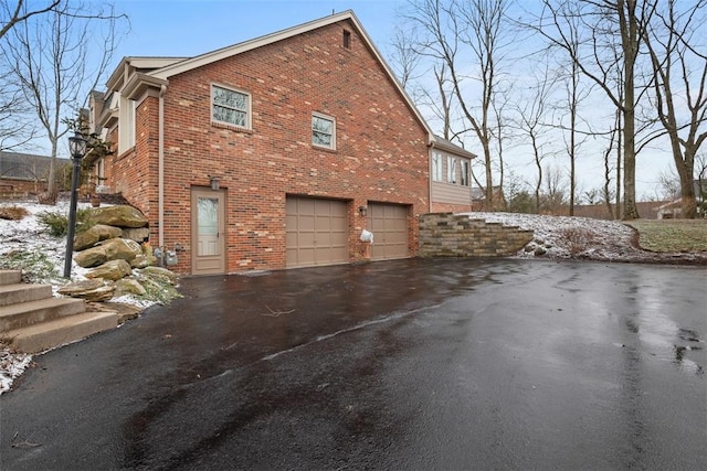 view of home's exterior with brick siding, aphalt driveway, and a garage