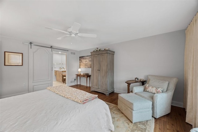 bedroom featuring a barn door, wood finished floors, and baseboards