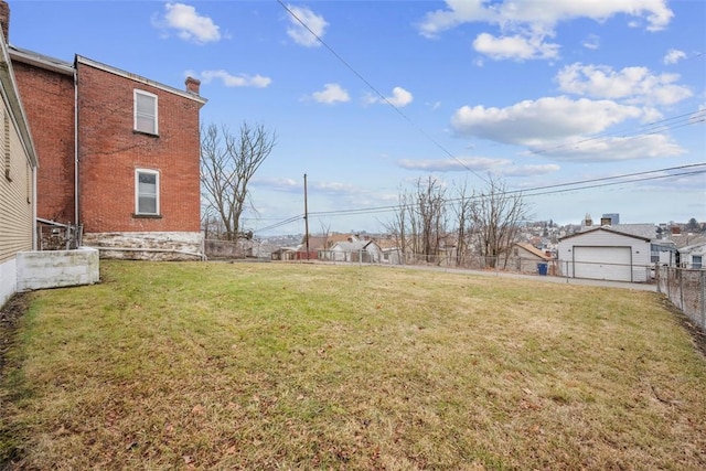 view of yard featuring a residential view, a detached garage, an outdoor structure, and fence