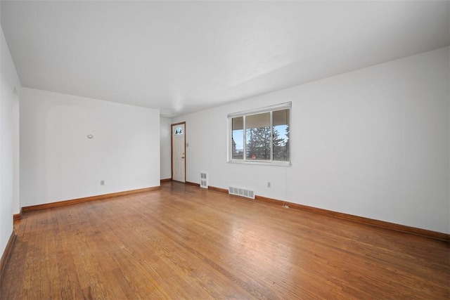 empty room featuring visible vents, baseboards, and wood-type flooring