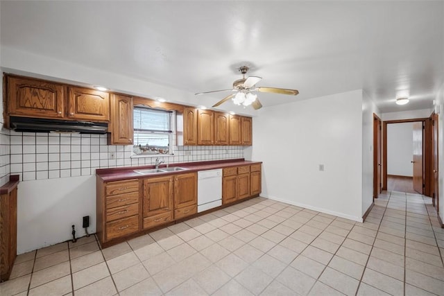 kitchen featuring brown cabinets, a sink, white dishwasher, light tile patterned floors, and decorative backsplash