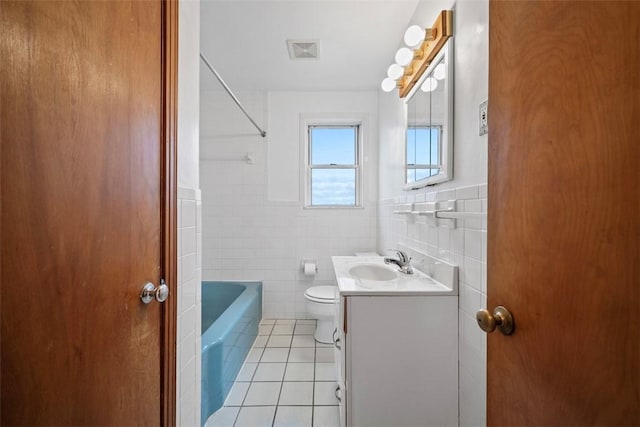 bathroom with visible vents, toilet, tile walls, tile patterned flooring, and vanity