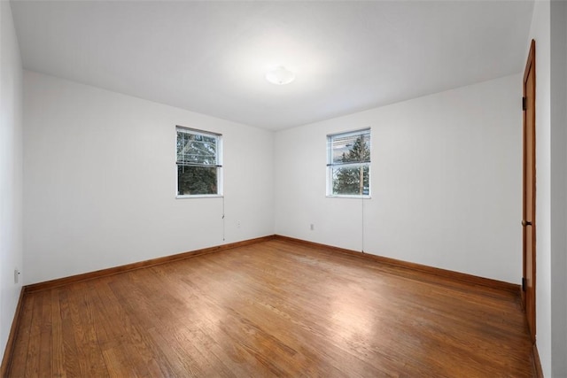 spare room with plenty of natural light, baseboards, and wood finished floors