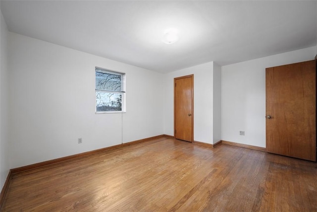 spare room featuring baseboards and light wood finished floors