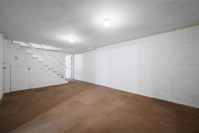 finished basement featuring tile patterned floors, stairway, and concrete block wall