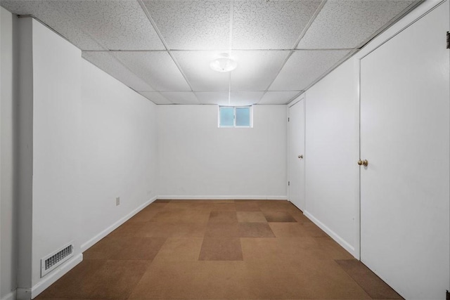 basement featuring a drop ceiling, visible vents, and baseboards