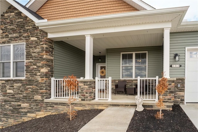 property entrance with a porch, stone siding, and a garage
