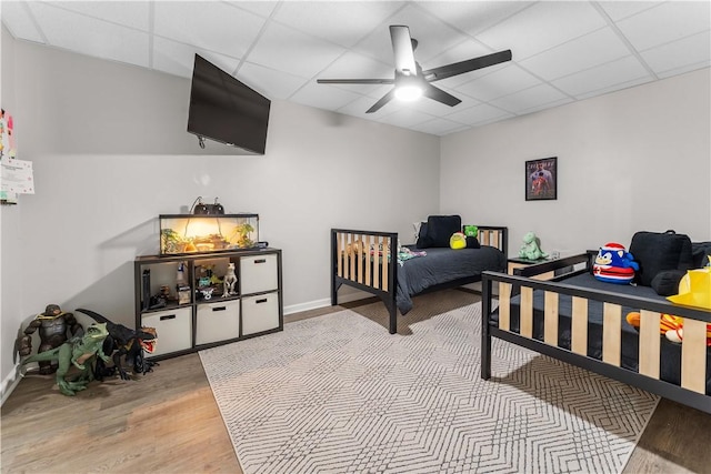 bedroom with baseboards, a paneled ceiling, wood finished floors, and a ceiling fan