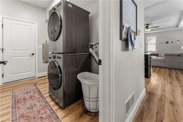 laundry room with visible vents, stacked washer and dryer, laundry area, light wood-style flooring, and a ceiling fan