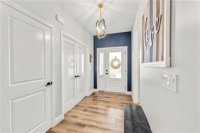 entryway featuring a notable chandelier, light wood-style floors, and baseboards