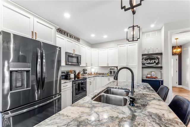 kitchen with visible vents, black appliances, pendant lighting, a sink, and white cabinetry