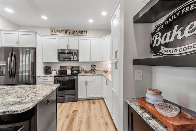 kitchen with white cabinets, light stone counters, and appliances with stainless steel finishes