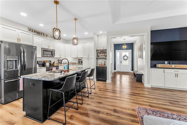 kitchen with stainless steel appliances, light wood finished floors, a breakfast bar, and white cabinetry