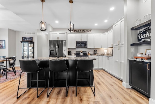 kitchen with a center island, white cabinets, light stone counters, and stainless steel appliances