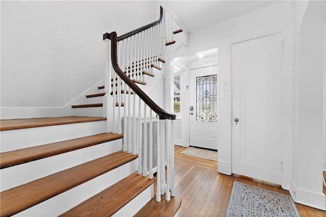 entrance foyer with baseboards, ornamental molding, stairs, and light wood finished floors