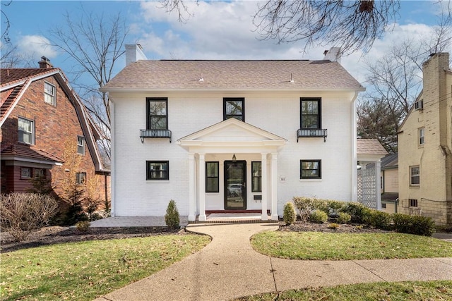 view of front of home featuring brick siding, a chimney, and a shingled roof