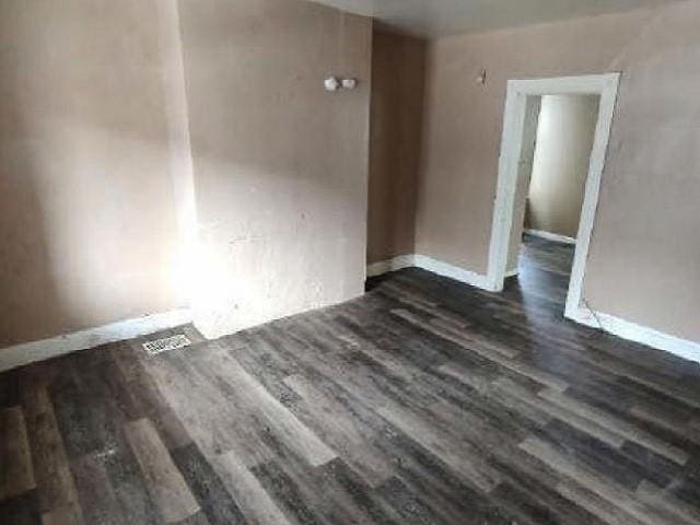 empty room featuring baseboards and dark wood-style flooring