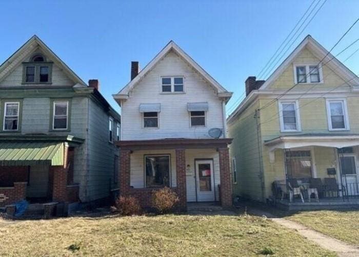 view of front facade with a front lawn, a porch, and a chimney