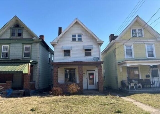 view of front facade with a front lawn, a porch, and a chimney