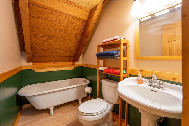 full bathroom with a freestanding bath, toilet, wood finished floors, and a sink