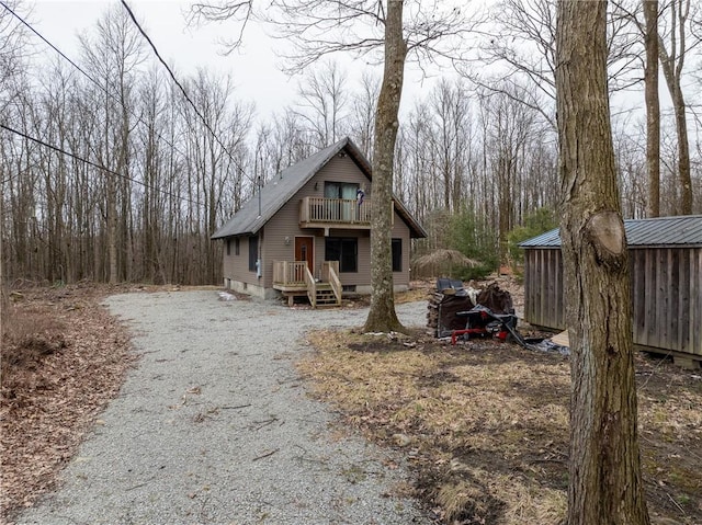 view of front of house with crawl space, gravel driveway, and a balcony