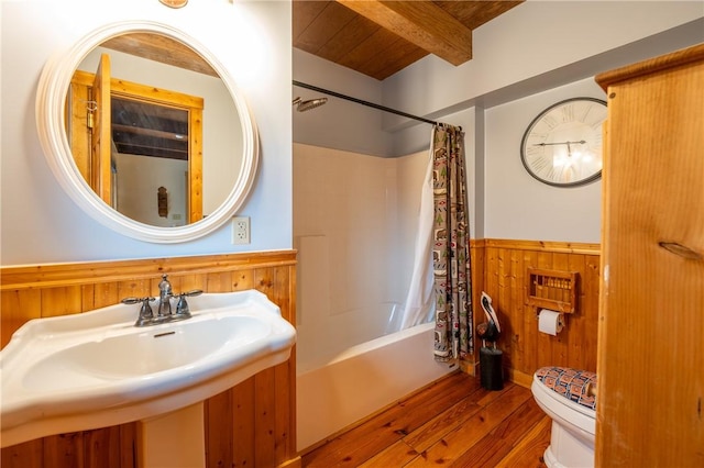 bathroom with beam ceiling, hardwood / wood-style flooring, wood walls, wainscoting, and toilet