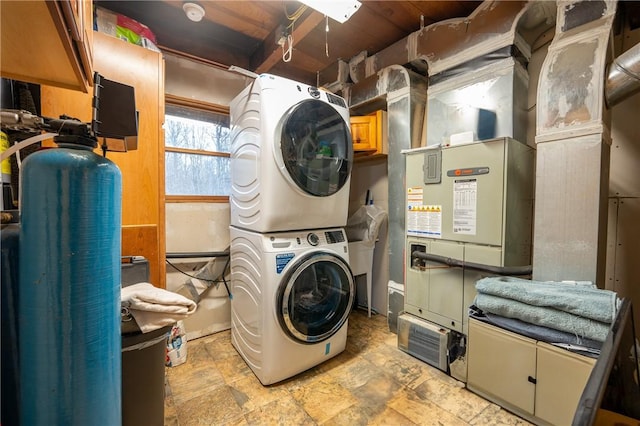 laundry area with laundry area, stone finish flooring, and stacked washing maching and dryer