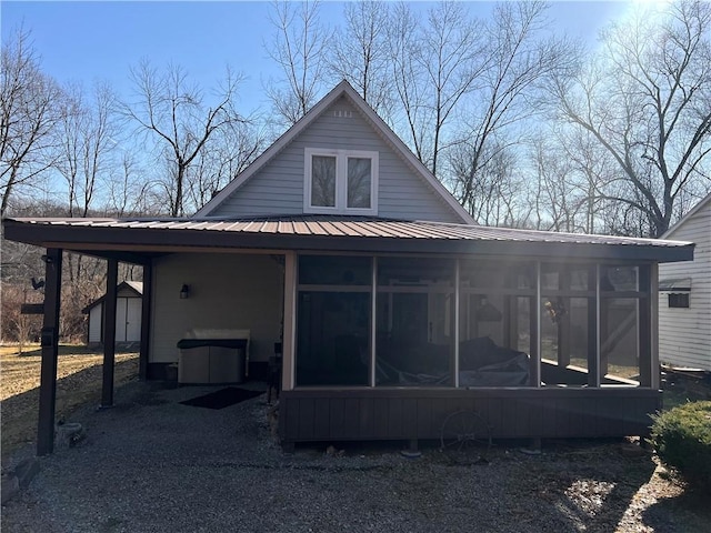 back of property with an outbuilding, a shed, metal roof, and a sunroom