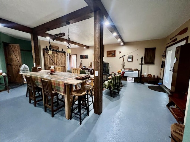 dining area with beam ceiling, concrete floors, and a barn door