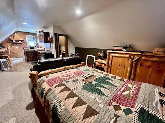 bedroom featuring lofted ceiling, light tile patterned flooring, a sink, wood walls, and light colored carpet