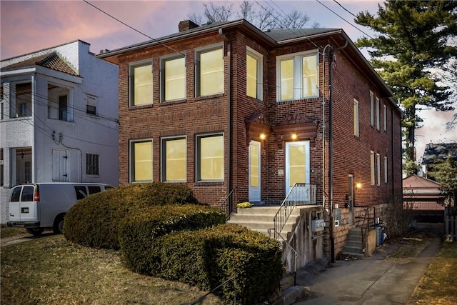 view of front of property with brick siding and a chimney