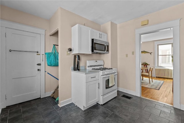 kitchen with visible vents, stainless steel microwave, gas range gas stove, radiator, and white cabinets